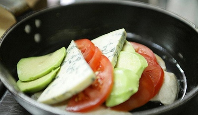Выложить на обжаренную курицу овощи слоями: помидор, авокадо, сыр