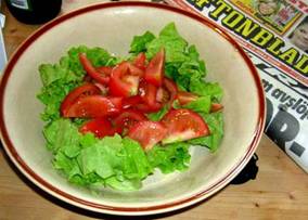 2.Порвите руками листья салата на мелкие кусочки, положите их в миску. Порежьте помидоры на маленькие кусочки, добавьте их в миску.