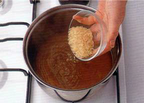 Влейте бульон в кастрюлю, медленно доведите до кипения и всыпьте рис. 